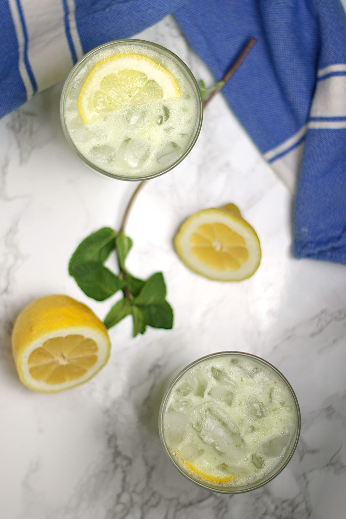 An overhead photo of two glasses of Middle Eastern Mint Lemonade with ice.