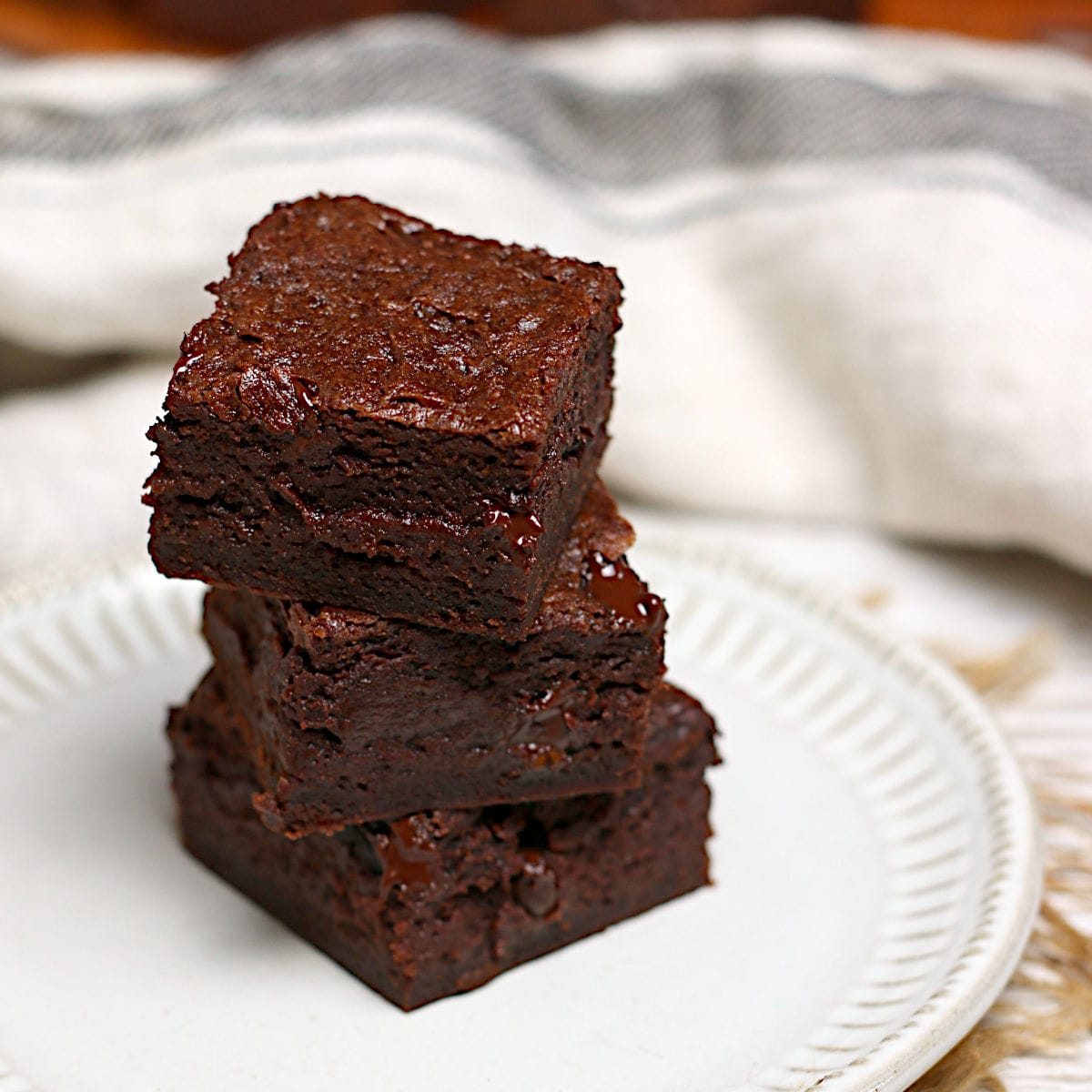 A stack of Mocha Fudge Vegan Brownies on a small white plate.