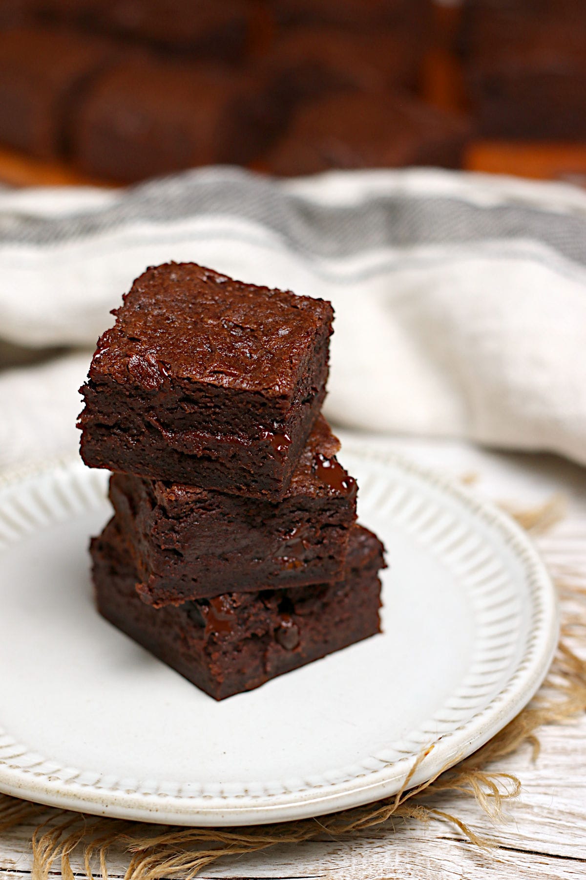 A stack of Mocha Fudge Vegan Brownies on a small white plate.
