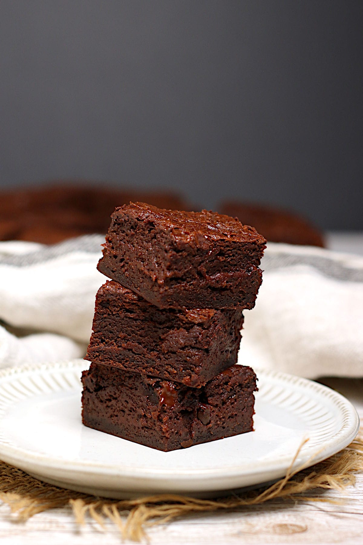 A stack of Mocha Fudge Vegan Brownies on a small white plate.