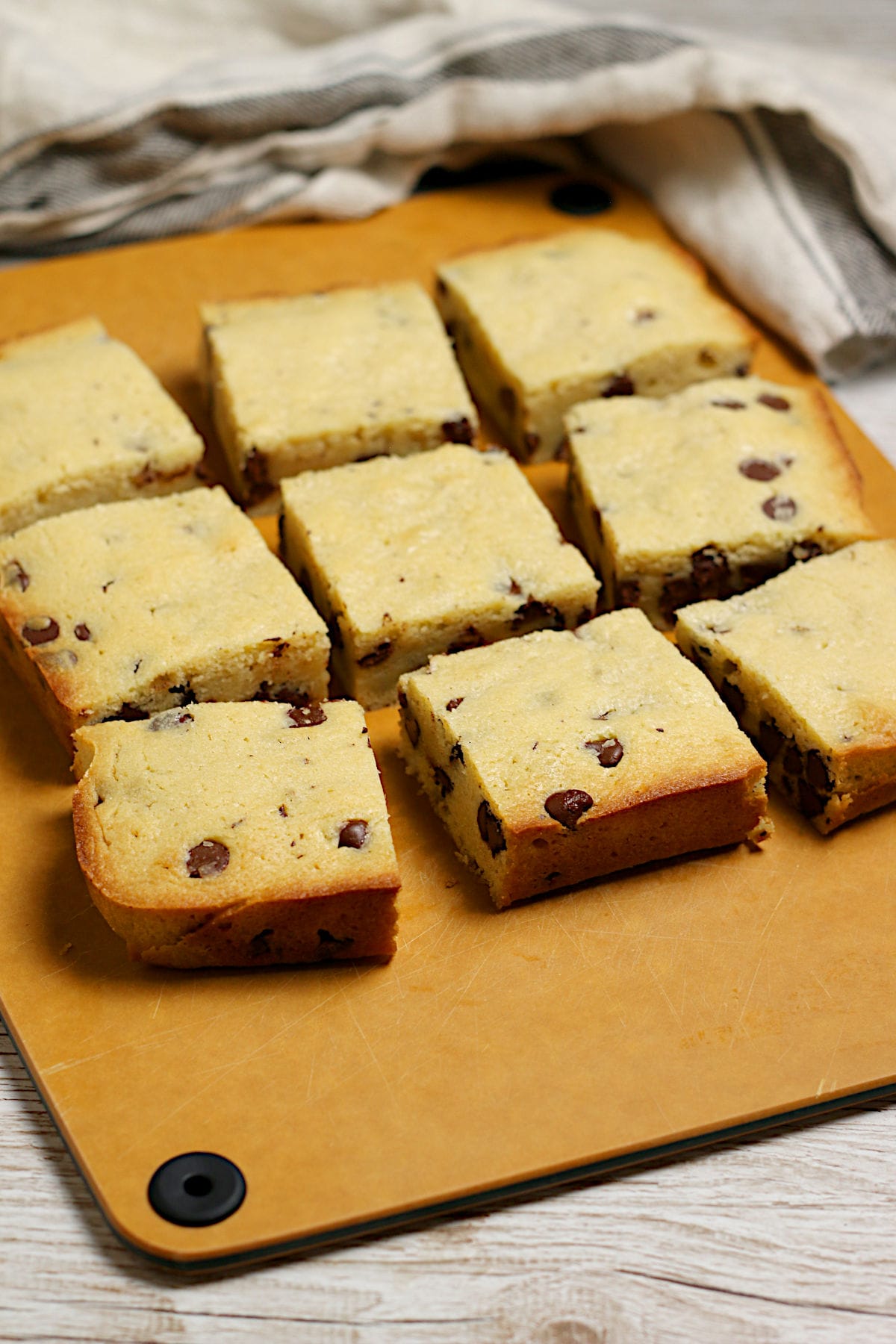 Nine white chocolate brownies cut into squares on a cutting board.