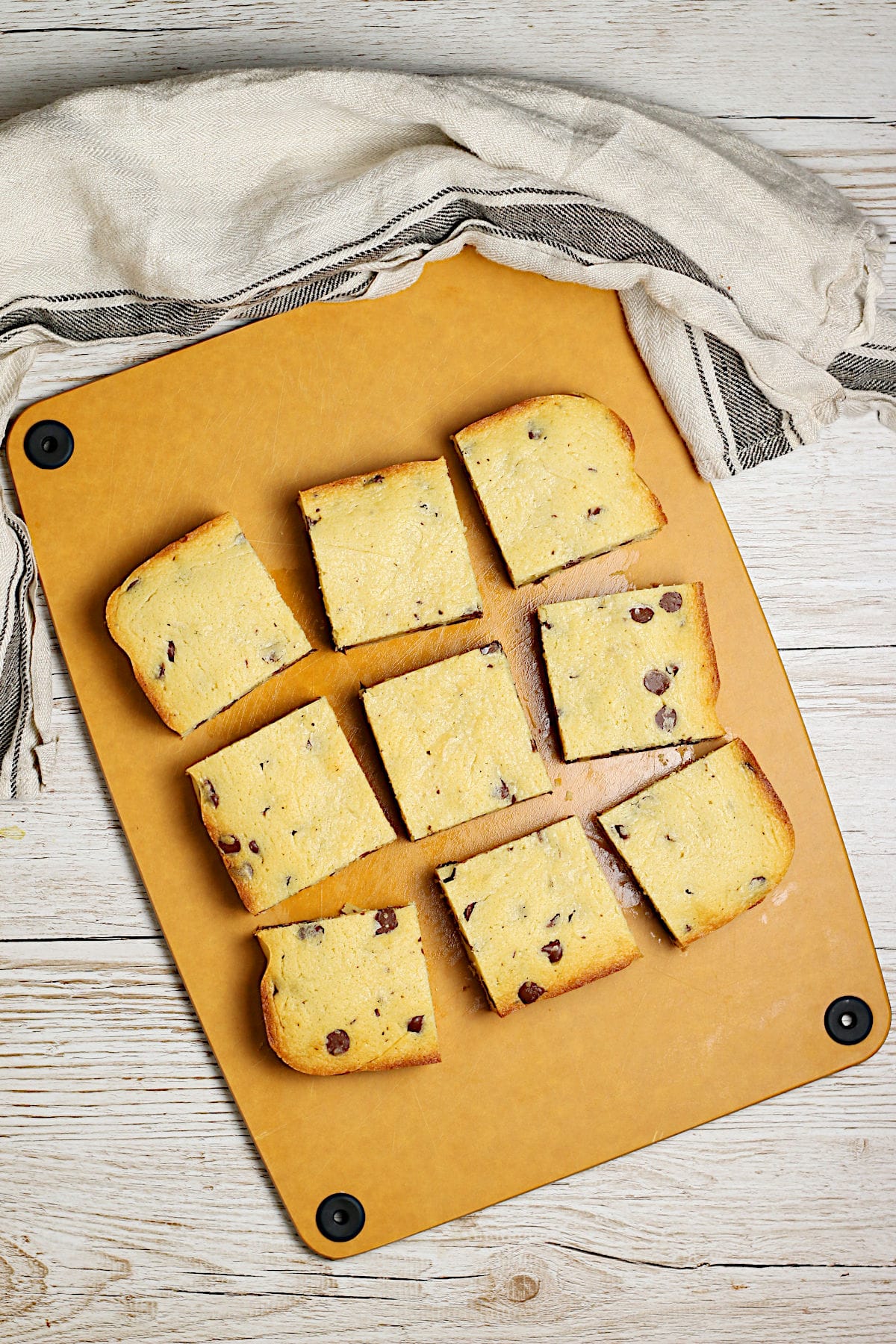An overhead photo of nine white chocolate brownies cut into squares on a cutting board.