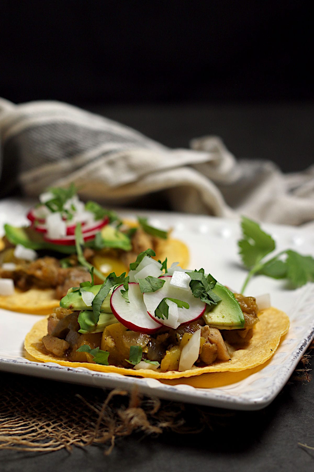 Two Green Chile Chicken tacos on a square white plate.