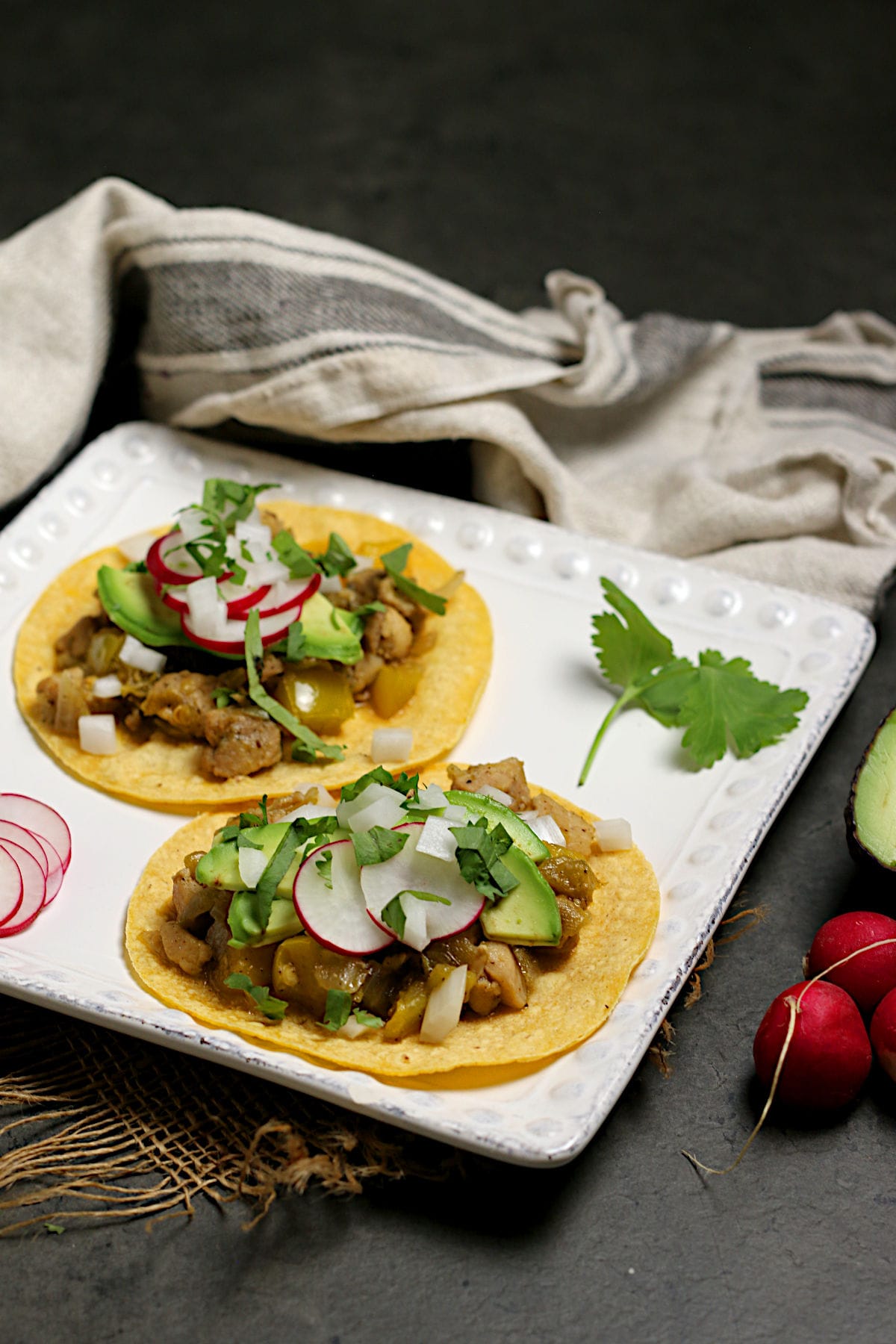 Two Green Chile Chicken tacos on a square white plate.
