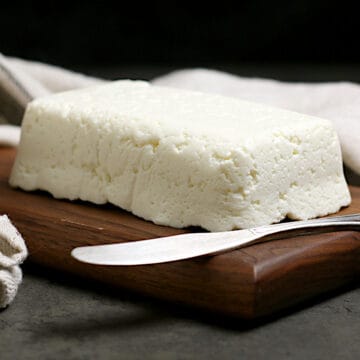 A block of Homemade Queso Fresco on a small wood cutting board.