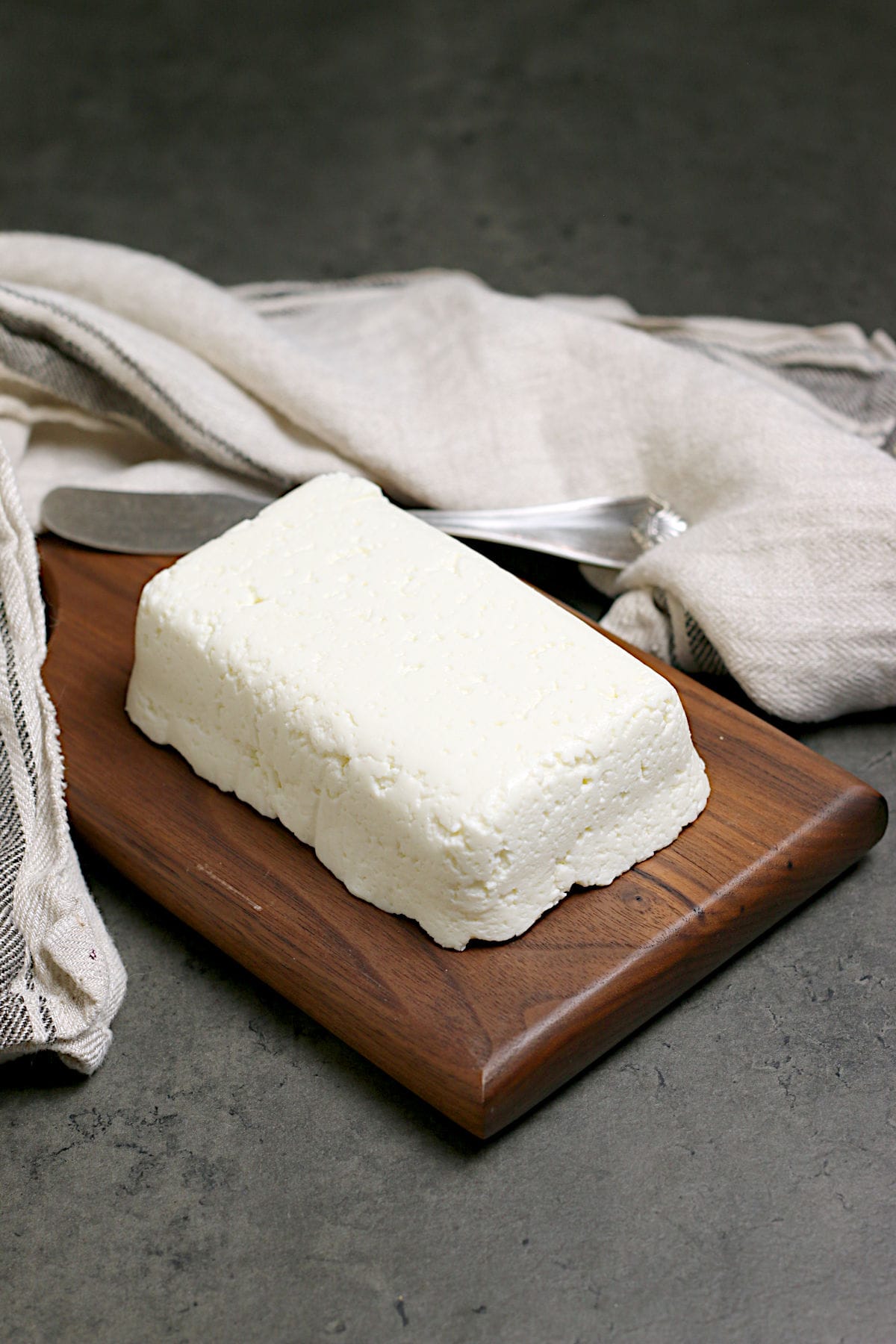 A block of Homemade Queso Fresco on a small wood cutting board.