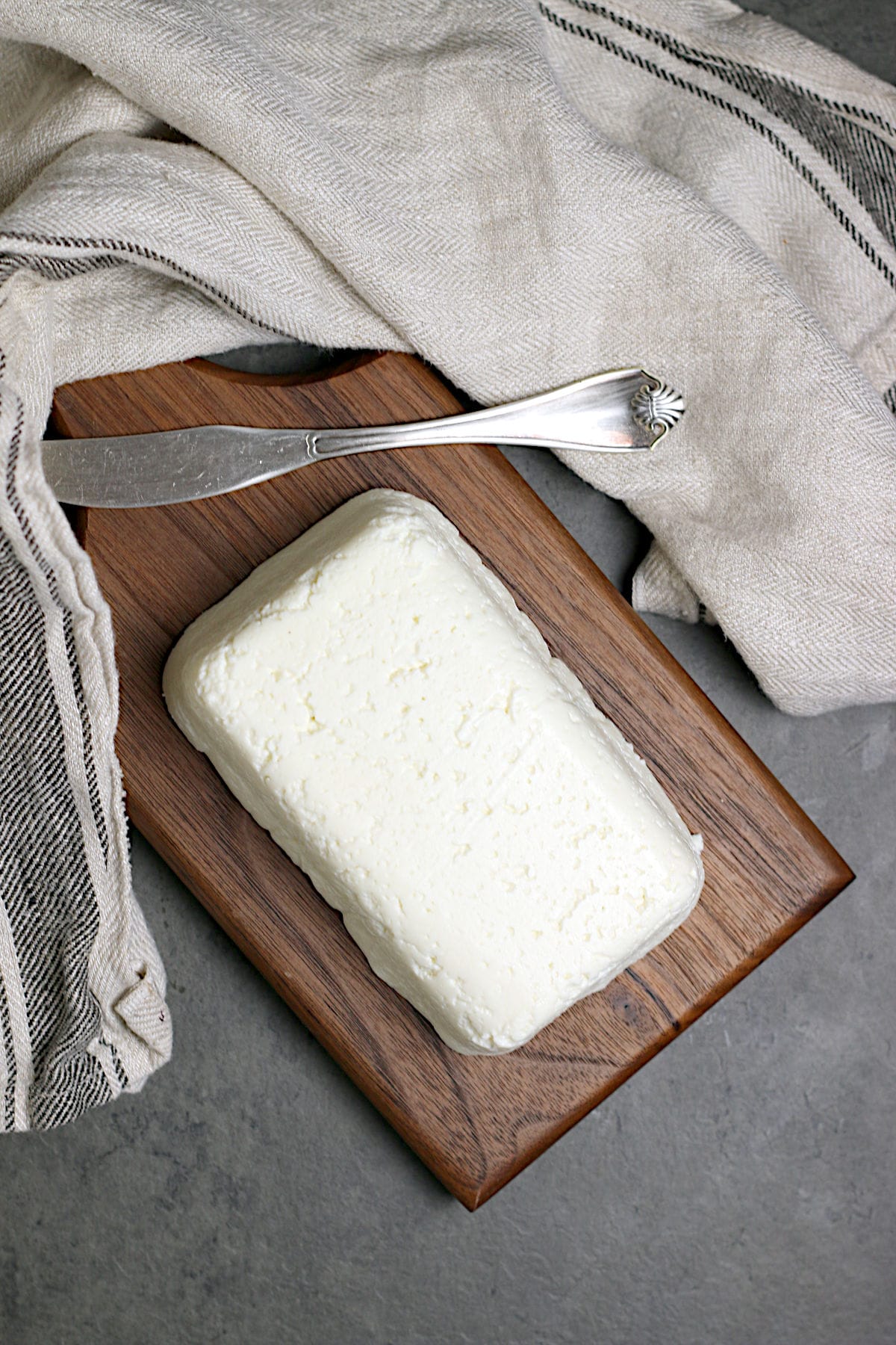 An overhead photo of a block of Homemade Queso Fresco on a small wood cutting board.