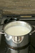 Curdled milk to make queso fresco in a saucepan on a stove.