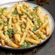A plate full of Pho-Inspired Fries topped with lime mayo and chopped herbs.