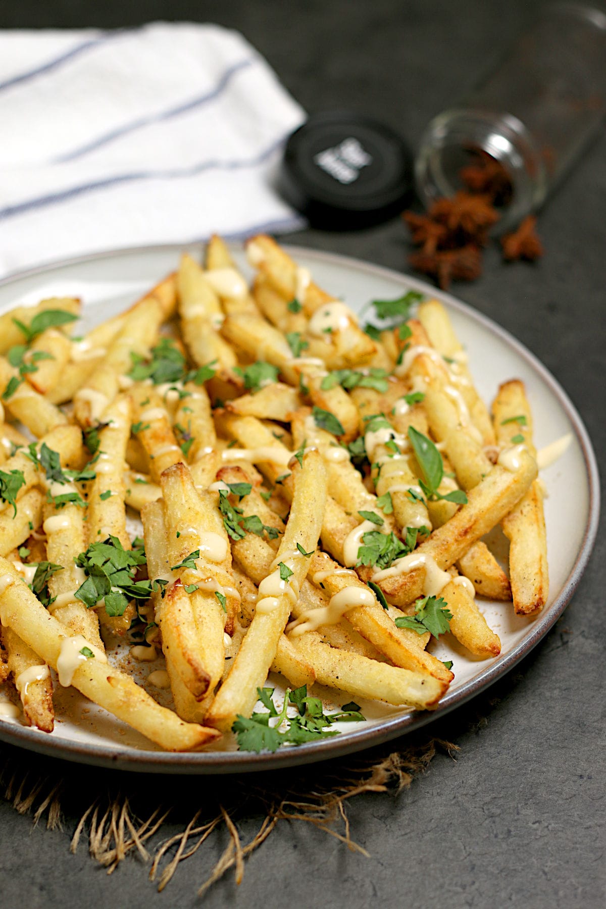 Pho-Inspired Fries (Phries) A plate full of Pho-Inspired Fries topped with lime mayo and chopped herbs.