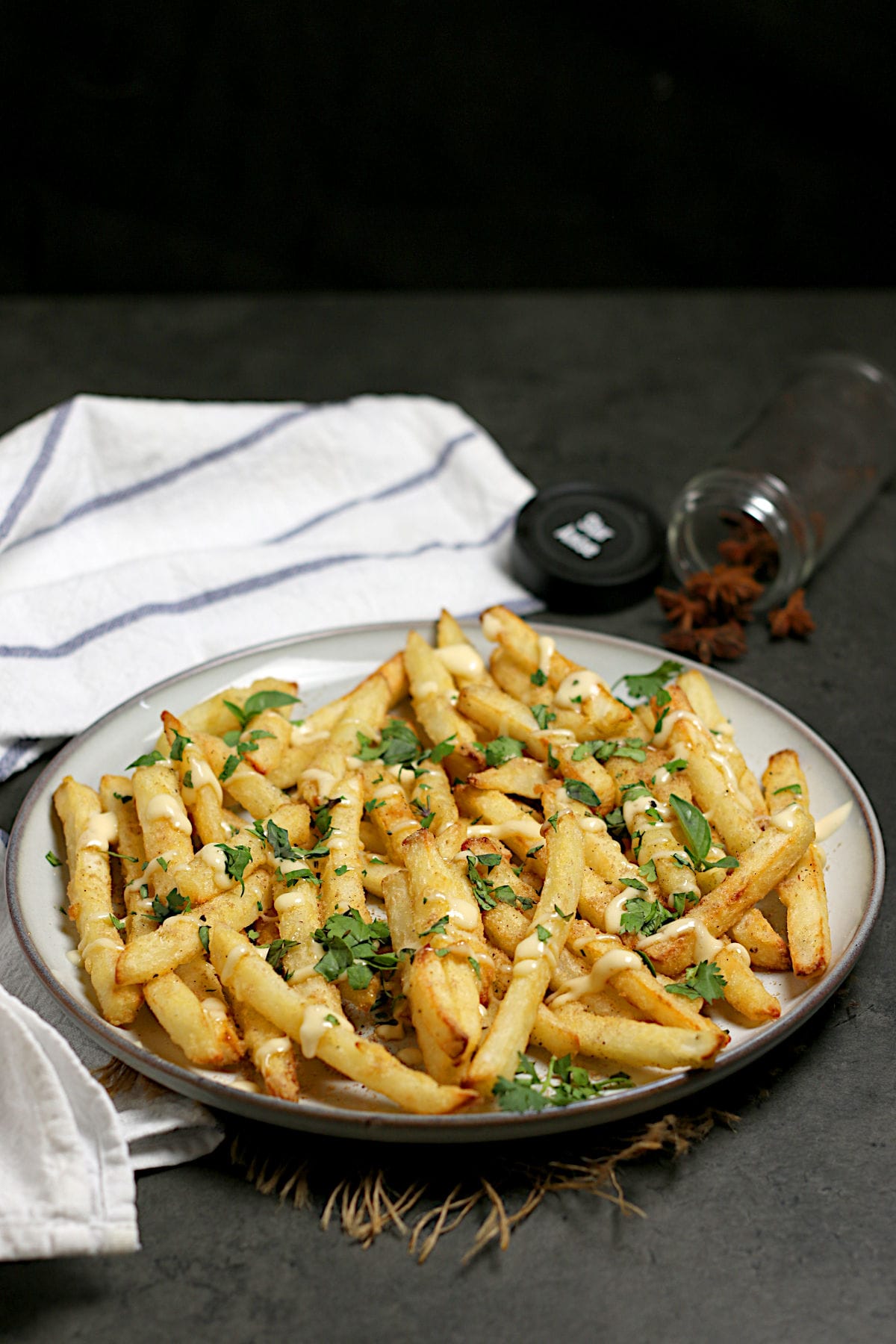 Pho-Inspired Fries (Phries) A plate full of Pho-Inspired Fries topped with lime mayo and chopped herbs.
