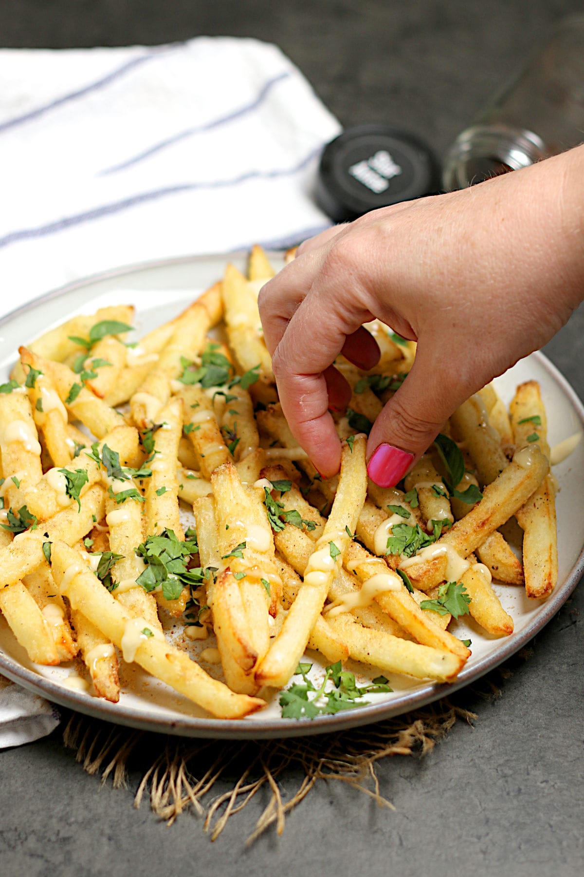 Pho-Inspired Fries (Phries) A hand picking up a Pho Fry from a large plate.