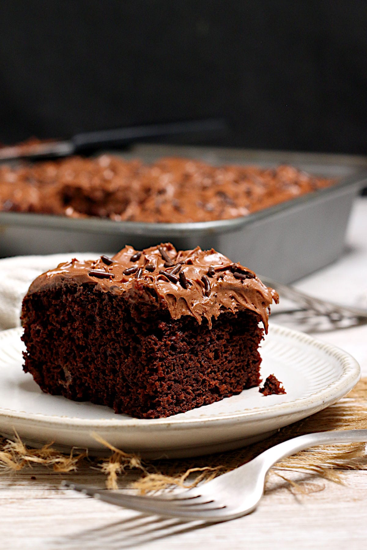 Easy Copycat Deep 'n Delicious Cake Frosting A slice of chocolate cake frosted with Easy Copycat Deep 'n Delicious Frosting on a small white plate.