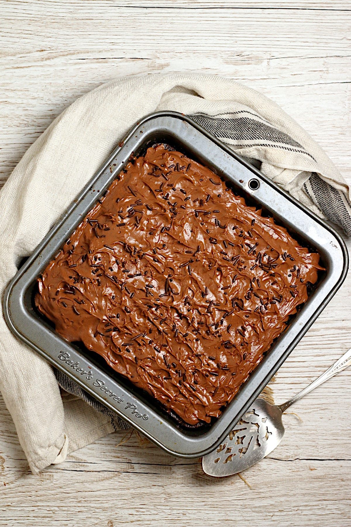 Easy Copycat Deep 'n Delicious Cake Frosting An 8x8" chocolate cake frosted with Easy Copycat Deep 'n Delicious Frosting in a baking pan.