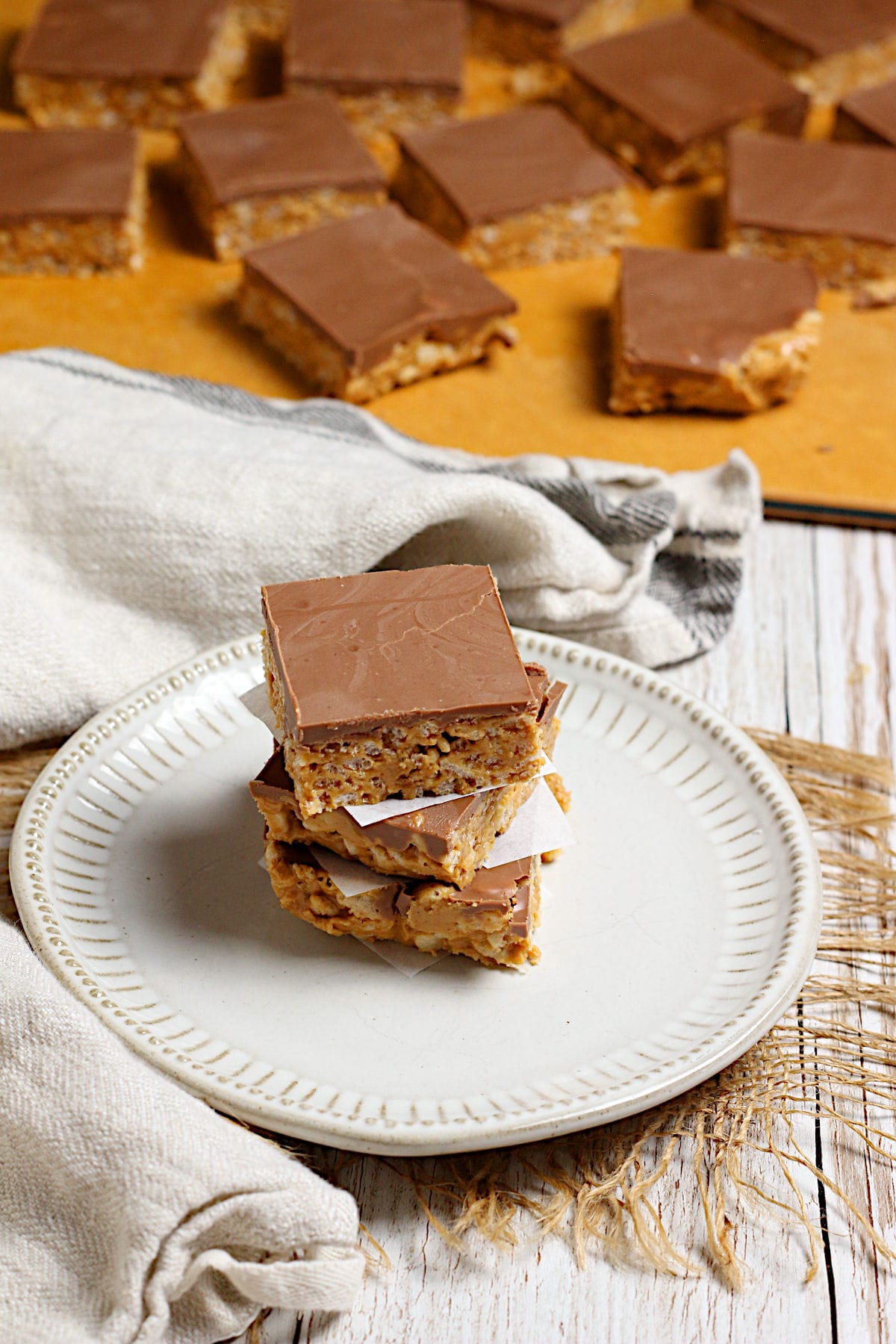 Chocolate Peanut Butter Crunch Bars A stack of Chocolate Peanut Butter Crunch Bars on a small white plate.