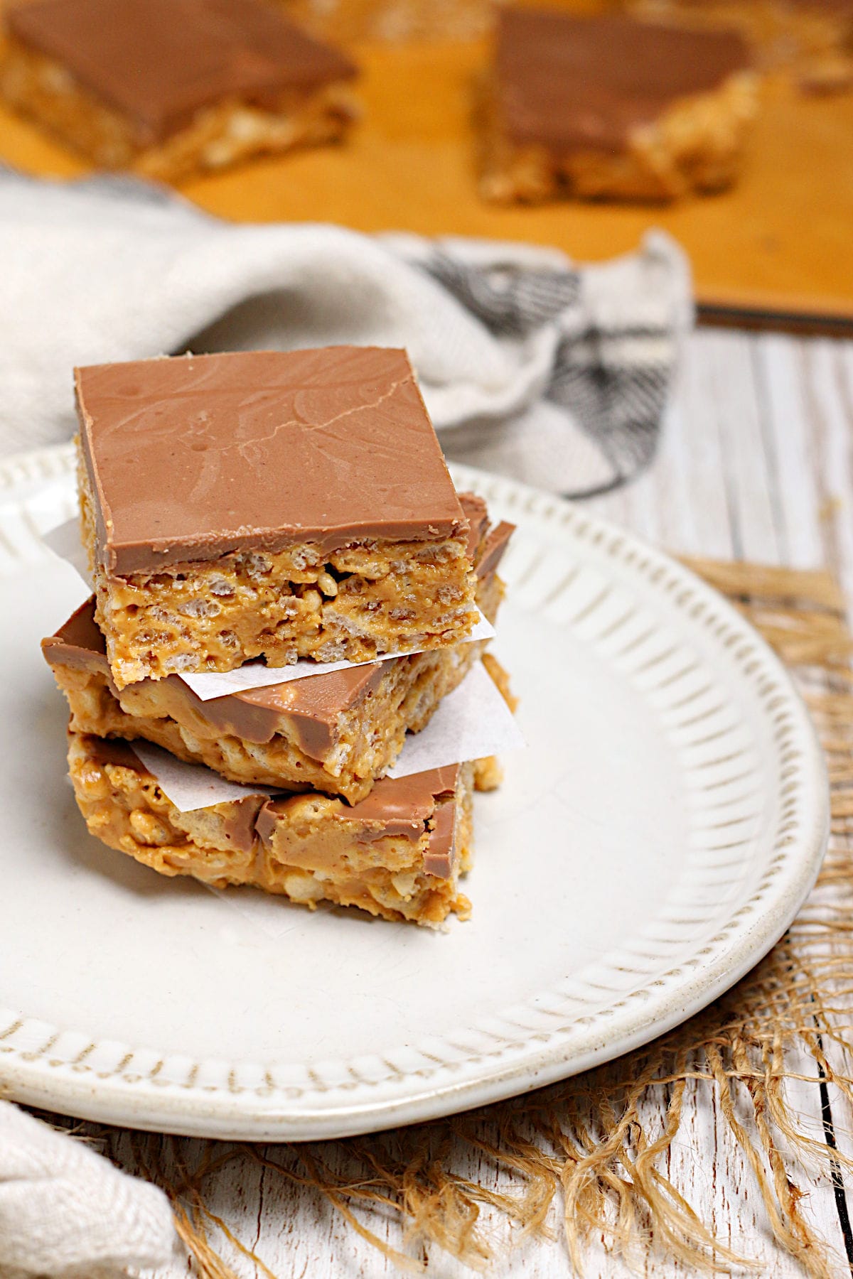 Chocolate Peanut Butter Crunch Bars A stack of Chocolate Peanut Butter Crunch Bars on a small white plate.
