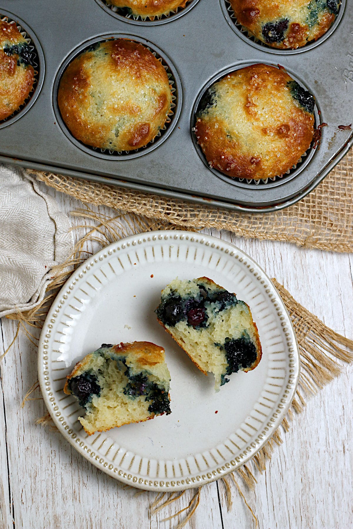 Blueberry Greek Yogurt Muffins An overhead photo of a Blueberry Greek Yogurt Muffin broken into two pieces on a small white plate.