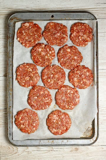 Homemade Breakfast Sausage Patties on a parchment-lined baking sheet before being cooked.